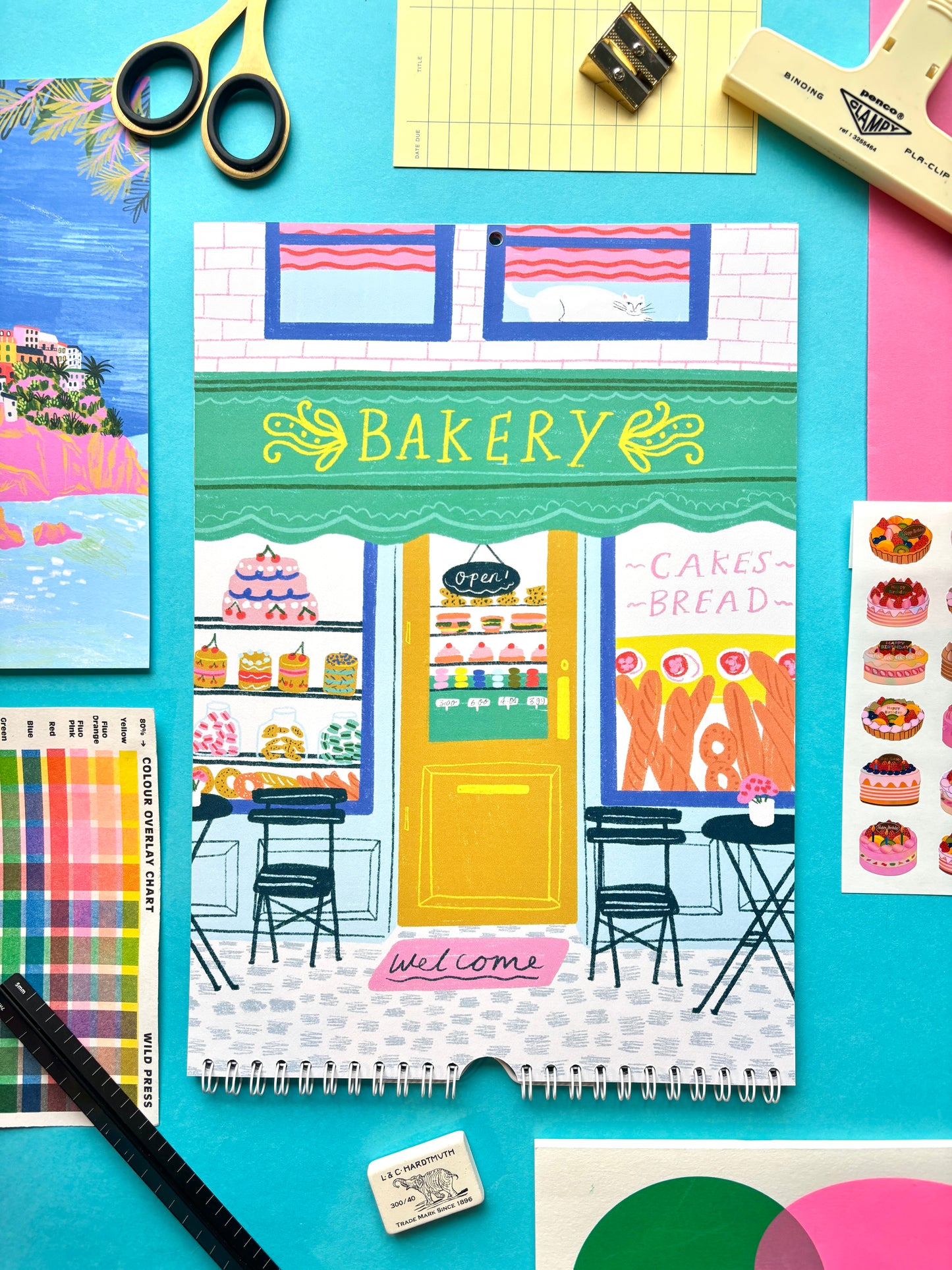 Notebook with bakery design on a colorful background with stationery items.