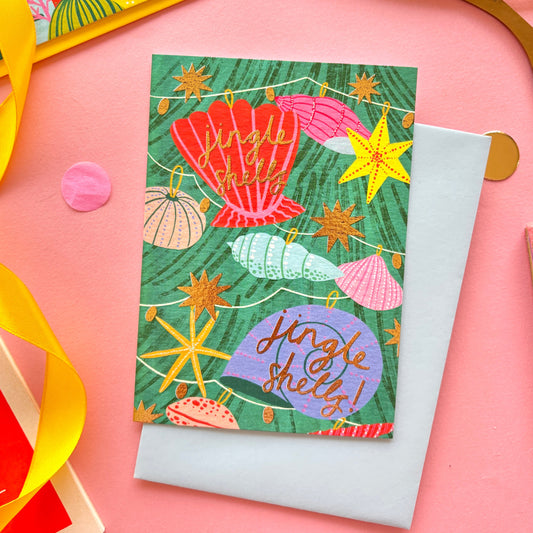 A christmas card with colourful shell lights around a colourful christmas tree surrounded by gold stars and hand-written text jingle bells, jingle bells – festive ocean-themed holiday card with bright yellow border on pastel background.