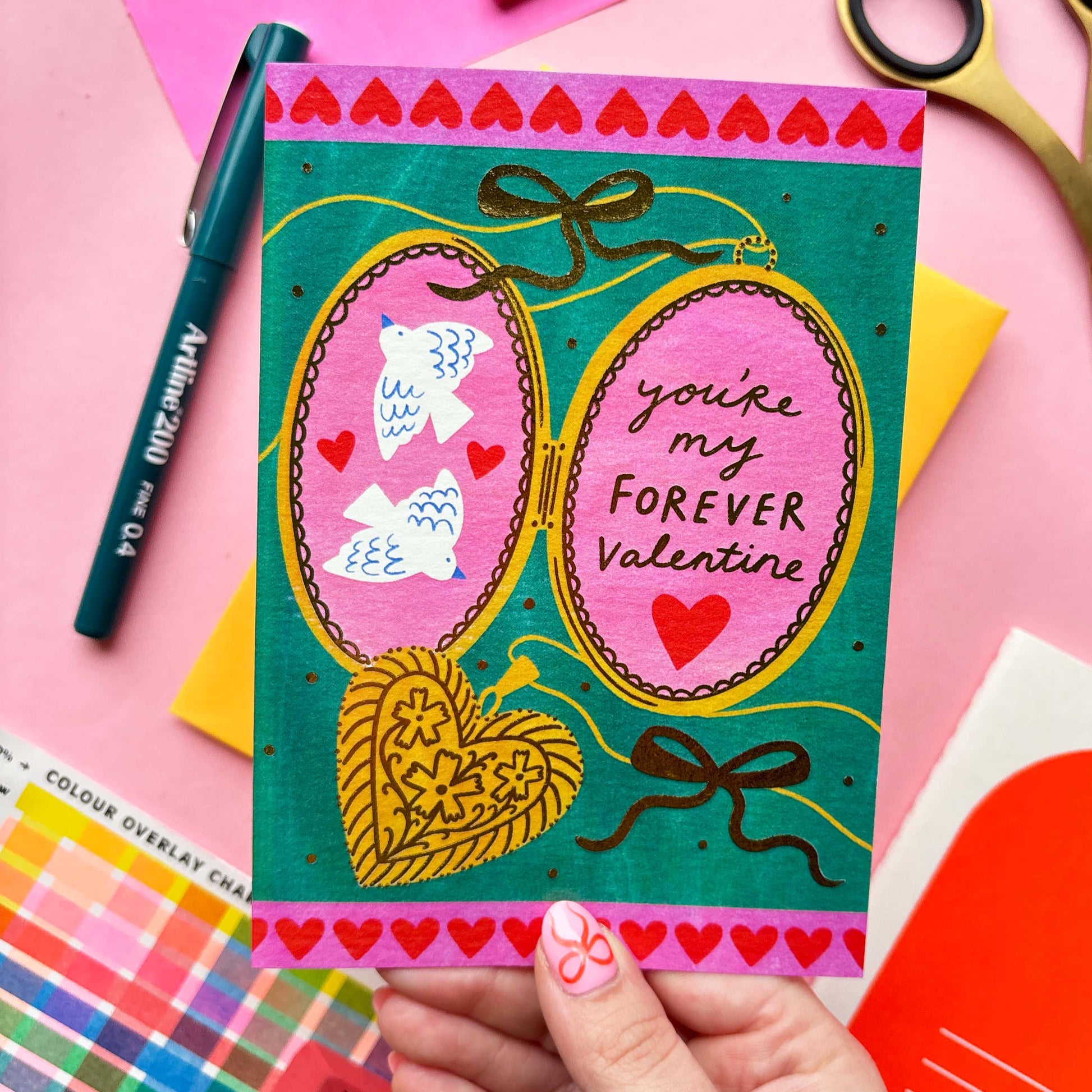 A picture of an illustrated valentines card by Kerrie McNeill a Northern irish illustrator. There is a locket with the words you're my favourite valentine on one side and the other are two doves surrounded my hearts.